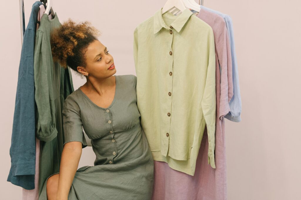 Woman in a boutique admiring beautiful linen clothes on hangers.